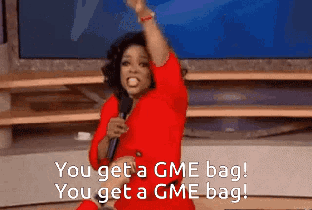 a woman in a red dress holds a microphone and says " you get a gme bag "