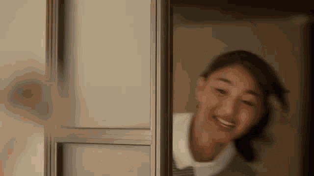 a woman is smiling and looking out a window .