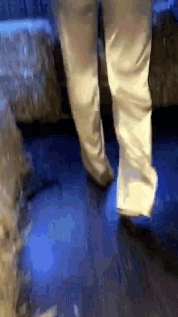 a person 's feet are walking on a blue floor