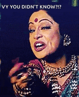 a woman with a red dot on her forehead is holding a cell phone and making a face .