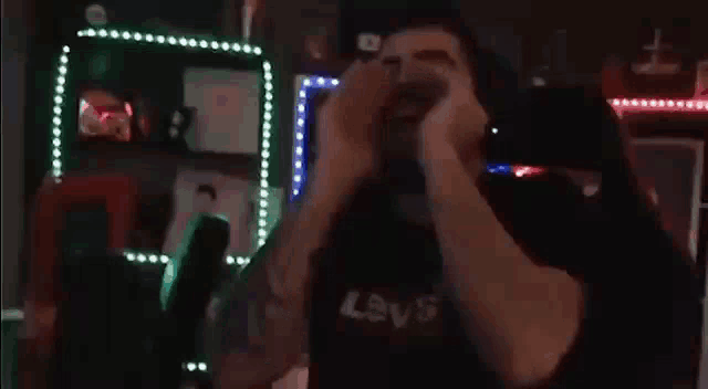 a man wearing headphones is screaming into a microphone while sitting in a gaming chair .