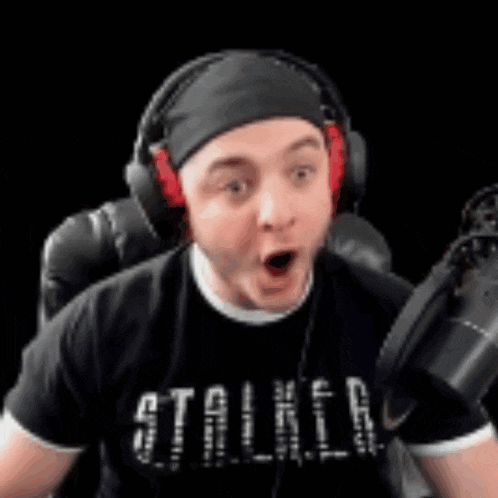 a man wearing headphones is sitting in front of a microphone .
