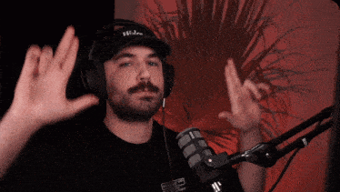 a man wearing headphones and a hat that says wolves stands in front of a microphone
