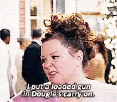 a woman is holding a gun in her hand and saying `` i put a loaded gun in dougie 's carry on ''