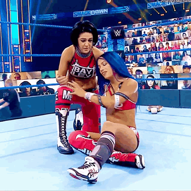 two women in a wrestling ring with one wearing a red top with the word bayley on it