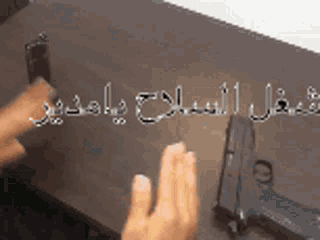 a person holding a gun on a table with arabic writing