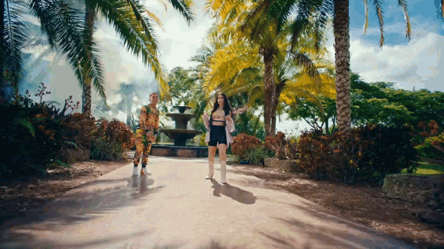 a man and a woman are walking down a path in a park