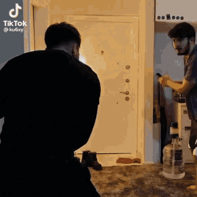 two men are standing in front of a door and a bottle of water