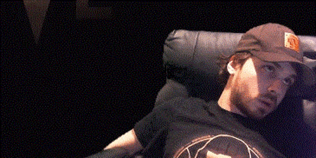 a man in a hat is laying on a couch with his arm outstretched