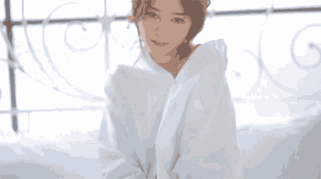 a woman in a white shirt is sitting on a bed and smiling