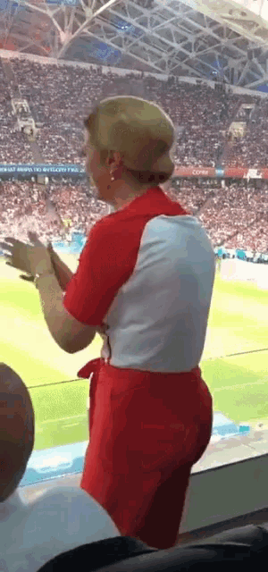 a woman in a red and white outfit is standing in a stadium