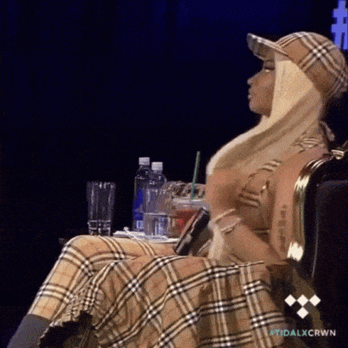 a woman is sitting in a chair wearing a plaid skirt and hat .