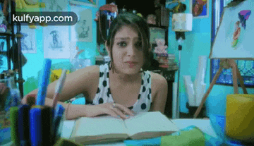 a woman is sitting at a desk with a book and a pen in her hand .