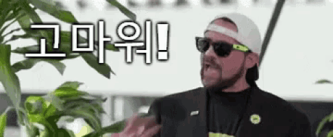 a man wearing sunglasses and a hat is standing in front of a plant with chinese writing on it .