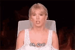 a woman in a white dress is sitting in a chair and saying oh , god .