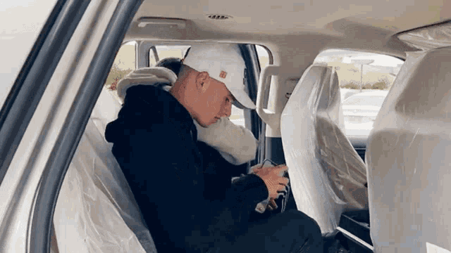 a man in a white hat is sitting in the back seat of a car