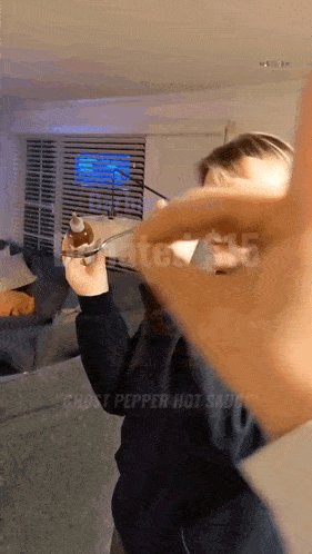 a person holding a bottle of ghost pepper hot sauce in their hand