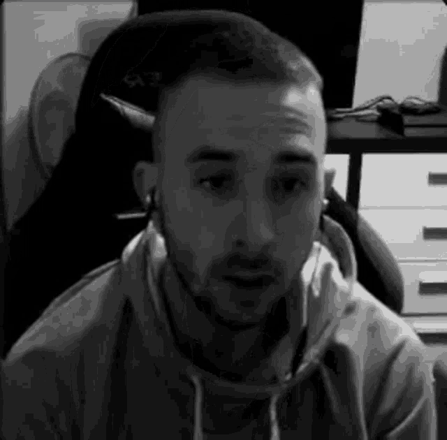 a man is sitting in a chair wearing headphones and a hoodie .