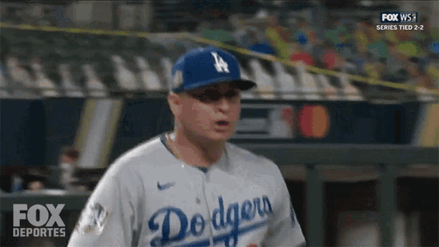a man wearing a dodgers baseball uniform is standing on the field .