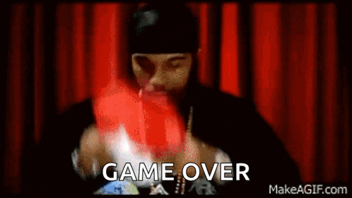 a man is holding a remote control in front of a red curtain with the words `` game over '' written on it .