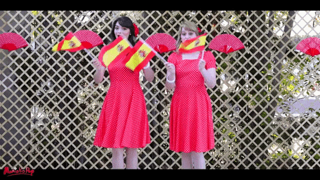 two women in red polka dot dresses are holding spanish flags and red umbrellas