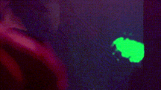 a close up of a woman 's face in a dark room with a green background .