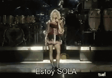 a woman singing into a microphone on a stage with the words estoy sola below her