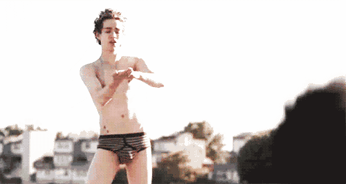 a shirtless young man in striped underwear is dancing