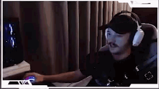 a man wearing headphones and a hat is sitting in a chair playing a video game .