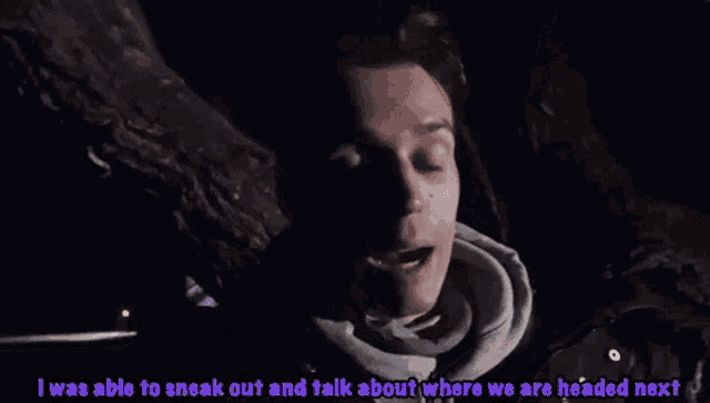 a man in a hoodie is talking to another man in a car at night .