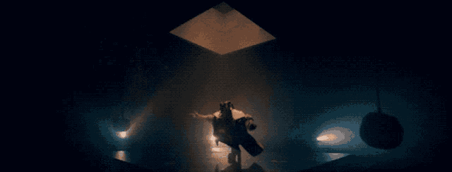 a person is standing in a dark room with a light shining through the ceiling