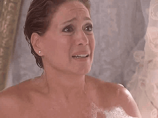 a naked woman is taking a bath with foam on her chest .