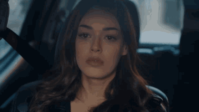 a woman sits in the back seat of a car