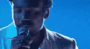 a man in a suit is singing into a microphone .