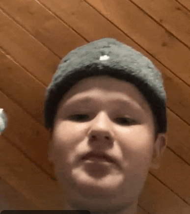 a young boy wearing a knitted hat is making a funny face