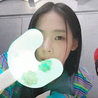 a woman holding a green object in front of her eye