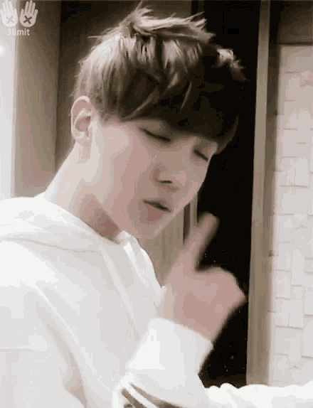 a young man wearing a white hoodie is giving a thumbs up sign .
