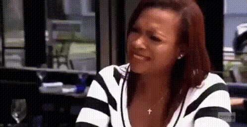 a woman in a black and white striped sweater is crying while sitting at a table in a restaurant .