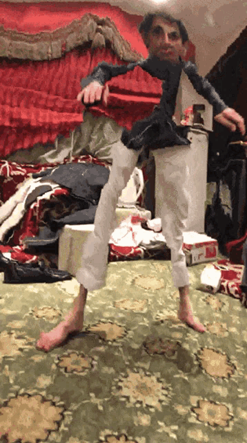 a man in a blue shirt and white pants is standing on a carpet