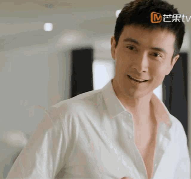a man in a white shirt is smiling in front of a sign that says m