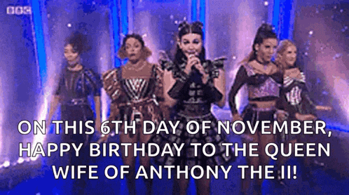 a group of women are standing on a stage singing into a microphone .