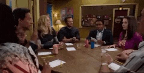 a group of people are sitting around a table in a room .