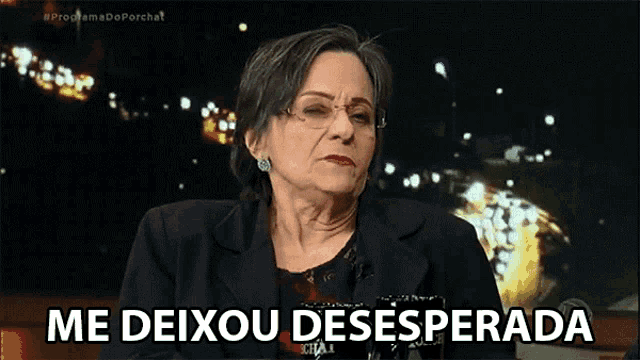 a woman with glasses is sitting in front of a sign that says me deixou desesperada