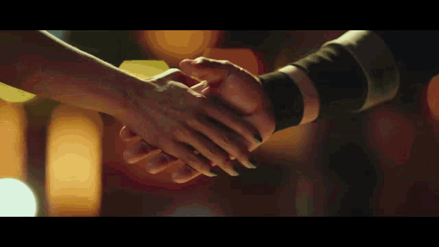 a man and a woman are shaking hands in a dark room