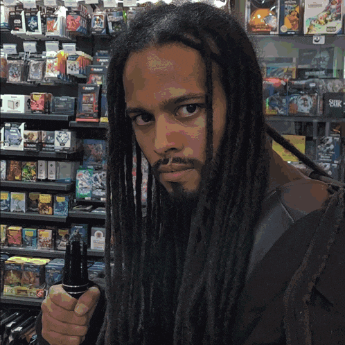 a man with dreadlocks and a beard is holding a sword in front of a shelf of toys