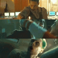 a man is holding a gun in front of a man with green hair .