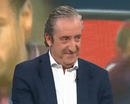 a man in a suit and white shirt is smiling and making a funny face