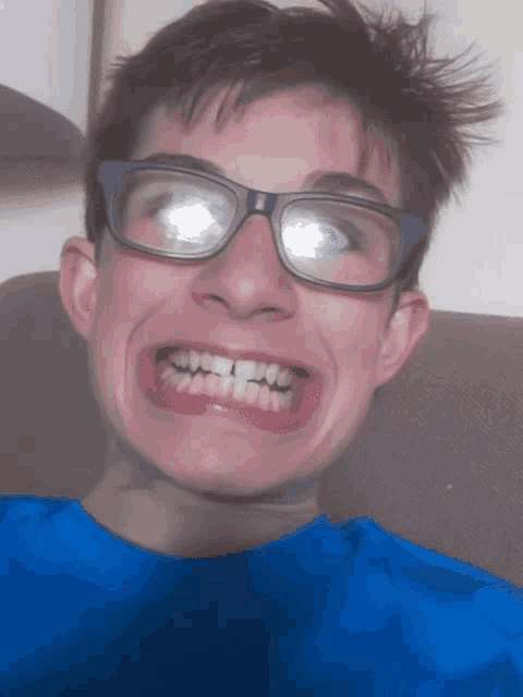 a young man wearing glasses and a blue shirt makes a funny face