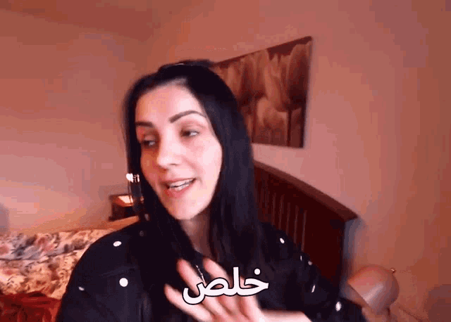 a woman is standing in front of a bed with arabic writing on her hand