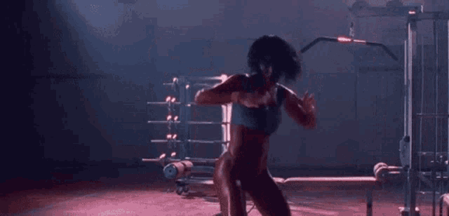 a woman in a bikini is standing in a gym with a barbell .